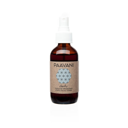 A brown glass bottle with a white spray nozzle labeled 'PAAVANI clarify' containing a clarifying toner with Neem and Rose.