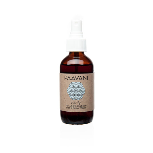 A brown glass bottle with a white spray nozzle labeled 'PAAVANI clarify' containing a clarifying toner with Neem and Rose.