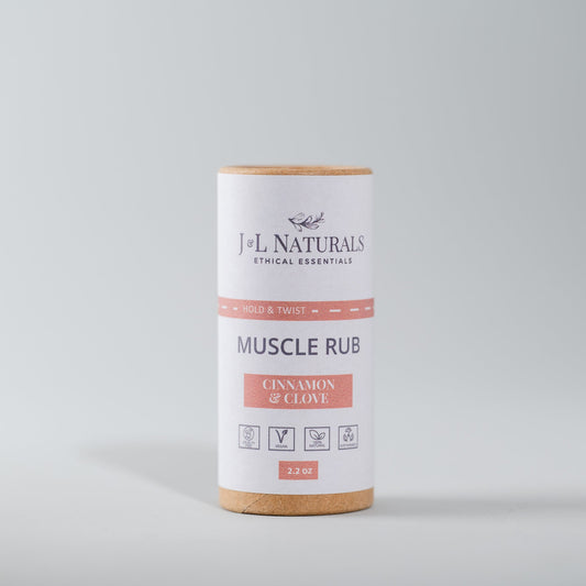 A push-up tube packaging of J+L Naturals muscle rub balm with label indicating cinnamon and clove flavors for soothing joint and muscle discomfort.